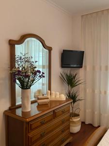 Cette chambre comprend une commode avec un miroir et une télévision. dans l'établissement Apartamento Conde, à Corcubión