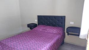 a bedroom with a bed with a purple bedspread at Hotel Bates in Villa General Belgrano