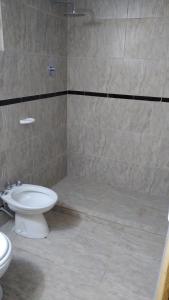 a bathroom with a white toilet and a shower at Hotel Bates in Villa General Belgrano