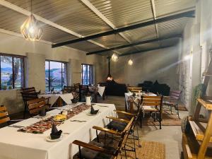 un restaurante con mesas y sillas blancas y ventanas en Little Sossus Lodge, en Sesriem