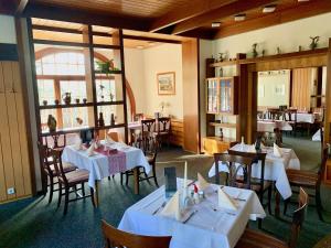 un comedor con mesas y sillas blancas y una habitación con en Forsthaus Siehdichum, en Dammendorf