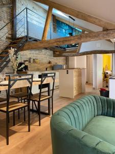 uma sala de estar com um sofá verde e uma mesa e cadeiras em Logement entier Noyers - L'Appart des Anges 2 em Noyers-sur-Serein