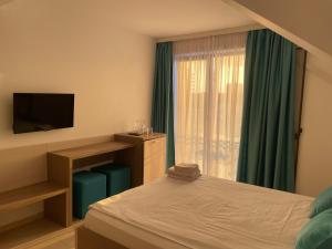 a bedroom with a bed and a tv and a window at Casa Jasmin in Năvodari