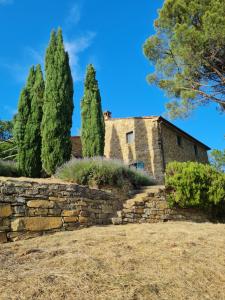 una antigua casa de piedra con árboles y una pared de piedra en COPPA DI SOPRA - Beautiful villa with superb view, en Santa Cristina