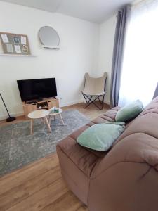 ein Wohnzimmer mit einem Sofa und einem Flachbild-TV in der Unterkunft Les Nuits Bonneuilloises Le Percheron in Breteuil