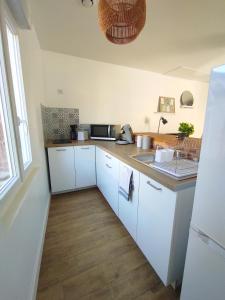 a kitchen with white cabinets and a counter top at Les Nuits Bonneuilloises Le Percheron in Breteuil