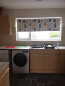 a kitchen with a dishwasher and a sink and a window at Seymour Apartment - Looe in Looe