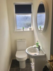 a bathroom with a toilet and a sink and two windows at Seymour Apartment - Looe in Looe
