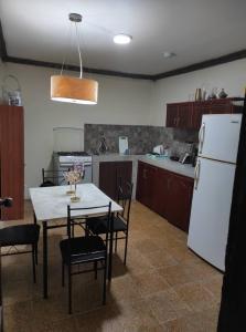 uma cozinha com uma mesa e um frigorífico branco em CASA MUY CONFORTABLE EN ZAMORA CHINCHIPE incluye desayuno em Zamora