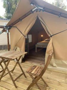 KT-0094 Magnífica Tienda Tipi - Camping Miramar Playa في توريديمبارا: خيمة بسرير وكرسي على سطح السفينة