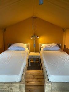 two twin beds in a room with a wall at KT-0094 Magnífica Tienda Tipi - Camping Miramar Playa in Torredembarra