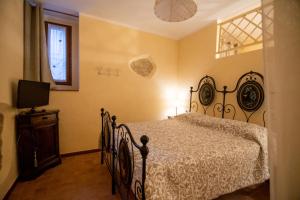 a bedroom with a bed and a television and a window at Nel vicolo dei Baci - Casa vacanze al Bacio in Spello