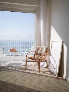 a chair in a room with a view of the ocean at Belle Vue Hôtel in Cavalaire-sur-Mer
