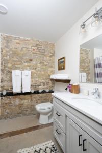 a bathroom with a sink and a toilet and a brick wall at Flexhome Brewery District 2BR Apt M11 - READ INFO in Milwaukee