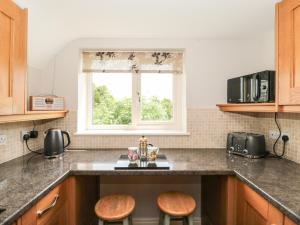 a kitchen counter with two stools and a window at West Moor Cottage Annex in Martock