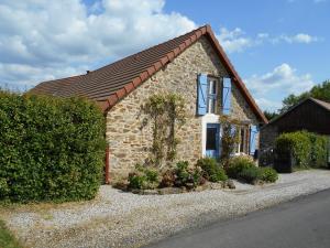 a small brick house with a window and bushes at Les Landes Gîte in Saint-Pardoux-Corbier