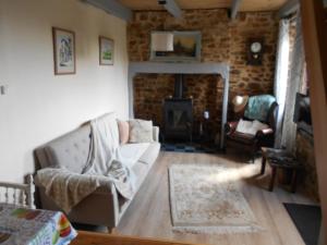 een woonkamer met een bank en een open haard bij Les Landes Gîte in Saint-Pardoux-Corbier