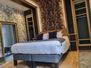 TreignacにあるHôtel La Brasserieの花柄の壁紙を用いたベッドルーム1室(キングサイズベッド1台付)