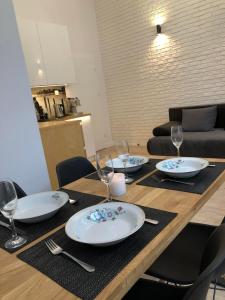 uma mesa de madeira com pratos e copos de vinho em Ogarna Elite Apart em Gdańsk