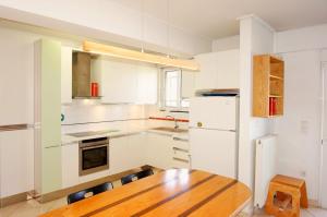 a kitchen with a wooden table and a white refrigerator at Piraeus Bright Apt in Piraeus