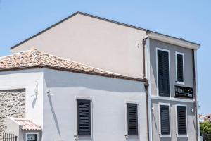 a white building with black shutters on it at B&B Màkari holiday home in Barcellona-Pozzo di Gotto