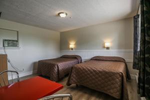 a room with two beds and a table and a table at Atlantic Motel in Moncton