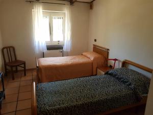 a room with two beds and a chair and a window at Chalet di montagna in Trasacco