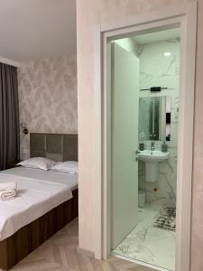 a bedroom with a bed and a bathroom with a sink at Appartament Home Plus in Tbilisi City