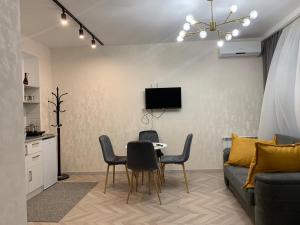sala de estar con sofá, mesa y sillas en Home Plus Apartments en Tiflis