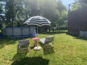 zwei Stühle und ein Regenschirm auf einem Hof in der Unterkunft Maison Fleurie in Coulonges
