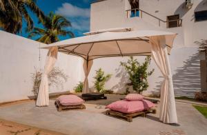 two beds under an umbrella in front of a house at Pousada Morada do Sol in Camocim