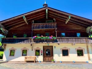 a large wooden building with flowers on the balcony at Pension Obwiesen in Kirchberg in Tirol