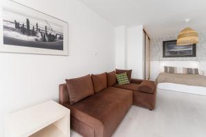 a living room with a brown couch and a bed at APT Nadmorskie in Kołobrzeg