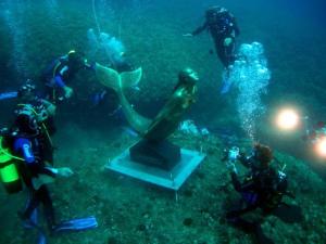 un grupo de personas tomando fotos de una estatua en el océano en Ortigia L'Antico Dammuso, en Siracusa