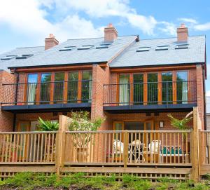 a large brick house with a deck with chairs at Hay Retreats in Hay-on-Wye