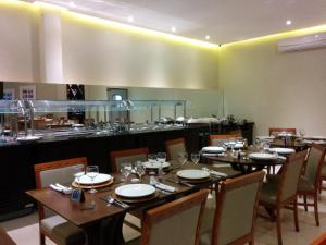 a dining room with a table and chairs and a kitchen at Itabuna Palace Hotel in Itabuna