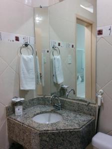 a bathroom with a sink and a mirror at Itabuna Palace Hotel in Itabuna