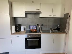 a kitchen with white cabinets and a stove top oven at Appartement 1 mit Küche und neuem Bad, frisch saniert in Friedrichskoog