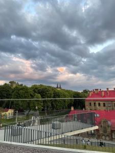 a fence in front of a building with a cloudy sky at Hostel Danylo Halytskyi in Lviv