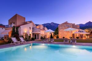 a pool with chairs and umbrellas in front of a building at Villas Marajo in Skala Potamias