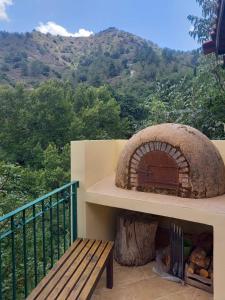 balcón con banco de madera y horno de pizza en Glykoharama Cottage, en Kalopanayiotis