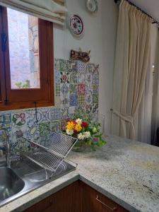 a kitchen counter with a sink and a vase of flowers at Glykoharama Cottage in Kalopanayiotis