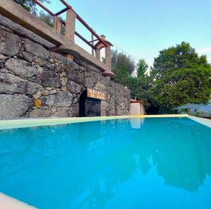 una piscina frente a una pared de piedra en Quinta da Roda - Natureza & Bem-Estar às Portas do Parque Nacional Peneda-Gerês, en Cela