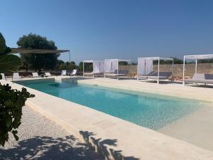 een groot zwembad met ligstoelen bij Masseria Capece in Cisternino
