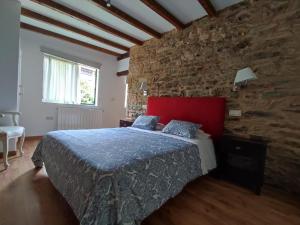 a bedroom with a bed with a brick wall at Casa Dos Cregos in Bascuas