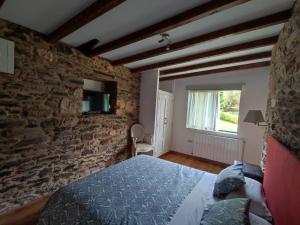 a bedroom with a bed and a stone wall at Casa Dos Cregos in Bascuas