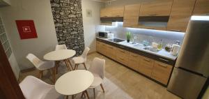 kuchnia z dwoma stołami i białymi krzesłami oraz lodówką w obiekcie Villa Eden & Restaurant w mieście Ełk