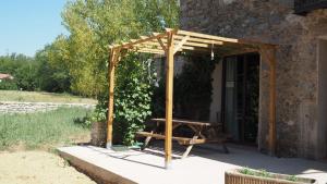a wooden pergola with a picnic table in front of a building at Ca n'Aliguer in Ripoll
