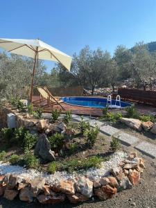 a swimming pool with an umbrella and some rocks at Lovin Göcek & Tiny House Lykia in Kertmeç