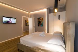 a bedroom with a white bed with a tv on the wall at Nikaj Premium Apart-Hotel in Vlorë